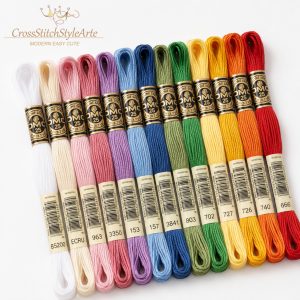 Colorful DMC embroidery floss skeins arranged on a clean white background for cross stitch and hand embroidery.